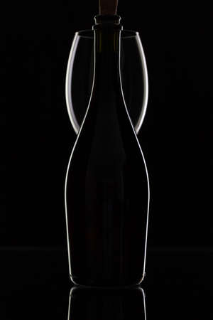 Empty bottle of wine and one glass on the black tableの写真素材