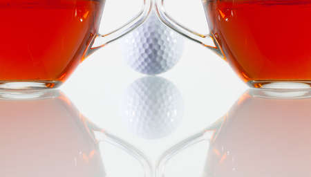 Two cups of tea and golf ball on the glass tableの写真素材