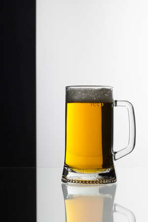 Glass of beer on the black and white background on the glass table