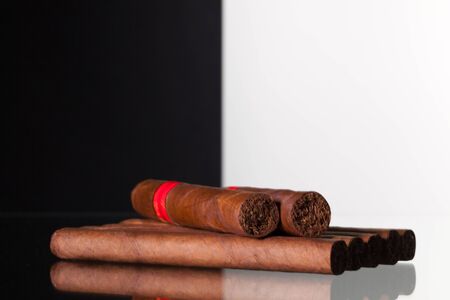 Different cigars on a  glass table and black and white background