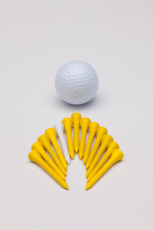 Wooden golf tees and white golf ball on the white backgroundの写真素材