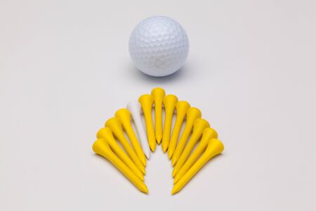 Wooden golf tees and white golf ball on the white backgroundの写真素材