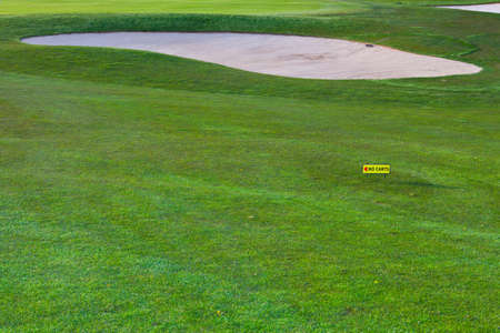 Sand bunker and a directional sign for golf cartsの写真素材