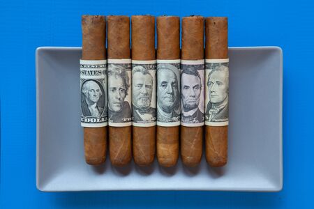 Gray ceramic dish and luxury Cuban cigars with US dollar banknotes on over blue  background, rectangle dishの写真素材