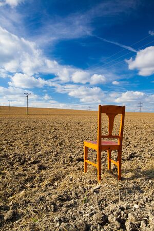 Old wooden chair on the empty field after harvestの写真素材