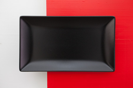 Empty black ceramic dish on over white  and  red wooden table, rectangle dishの写真素材