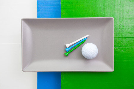 Gray ceramic dish with golf equipments on over white, blue and green wooden table, rectangle dishの写真素材