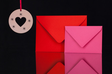 Red and pink   envelopes and Christmas decoration on the black glass tableの写真素材
