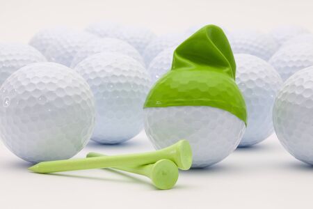 White golf balls with funny cap on the white background. Funny golf concept.の写真素材