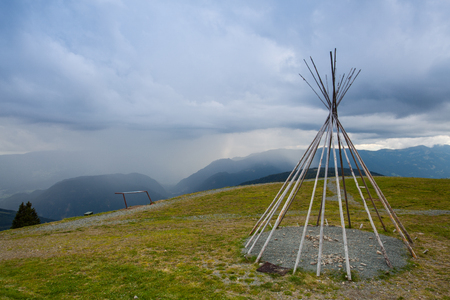 Typical American teepii on the hill before storm. Summer landscape in Gerlitzen Apls, Austria.