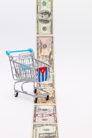 Strip of different us dollar banknotes and empty shopping trolley as a symbol of the american blockade in Cubaの写真素材