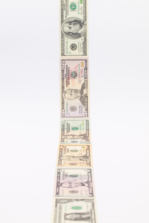 Strip of different us dollar banknotes on the white tableの写真素材