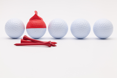 White golf balls with funny cap on the white background. Funny golf concept.の写真素材