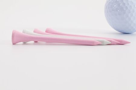 Pink wooden golf tees and golf ball on the white tableの写真素材