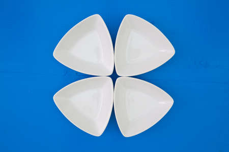 Empty triangular ceramic bowls for sushi on the blue wooden table
