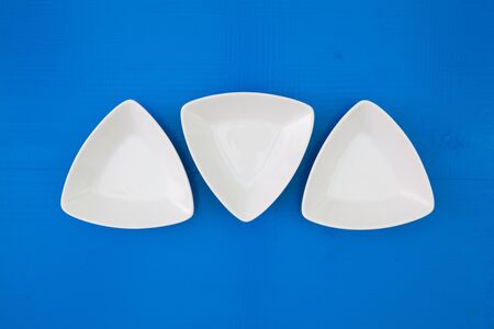 Empty triangular ceramic bowls for sushi on the blue wooden table