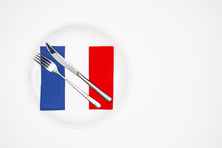 White plate and French flag of colorful napkins on the white wooden table.Top view. Flat Lay Image.の写真素材