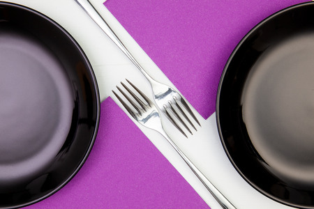 Black plates and purple napkins on the white wooden table.Top view. Flat Lay Image.の写真素材