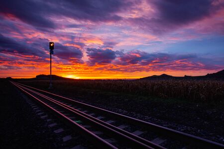 Morning train to the hell. Old Railway tracks running through a field stretch to rural countryside at dramatic sunrise.の写真素材