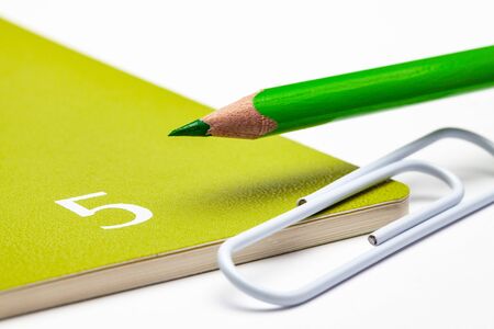 Organizer for the month of May, green  pencil and white paperclip on the white table.