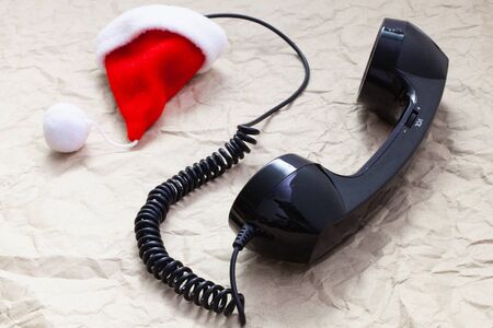 Old handset and Santa Claus cap on crumpled paper.  Winter holidays. Merry christmas and happy new year concept.の写真素材