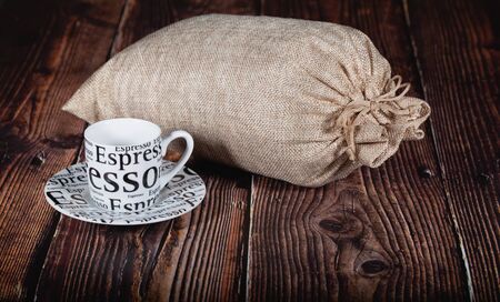 Cup of coffee and jute bag full od coffee beans on a wooden table .の写真素材