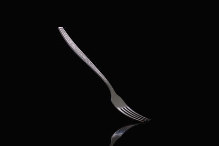 Old steel fork on black background. Metal fork on dark background close up.の写真素材
