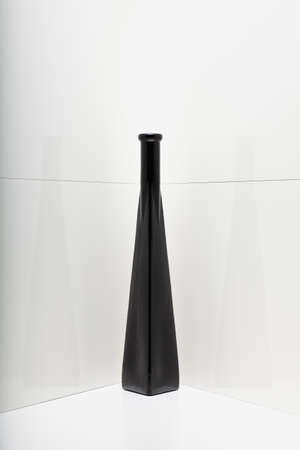 Black glass vase in a white corner.の写真素材