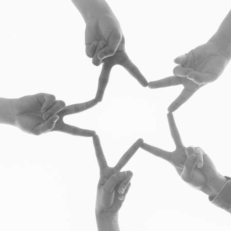 Black and white image of hands joining in a star shape on white background. Teamwork, unity and frienship concept. Look up view.の写真素材