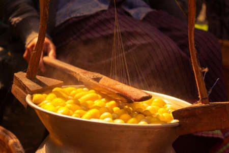 Thai woman boiling yellow silkwarm cocoons and making silk thread. A traditional way of hand made silk production.の写真素材