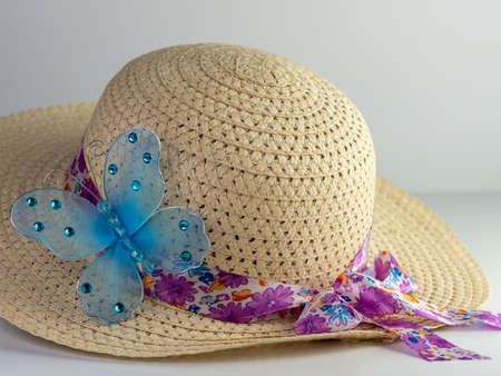 Spring hat with a flora ribbon tied around the brim and a blue mesh gem covered butterfly on the...