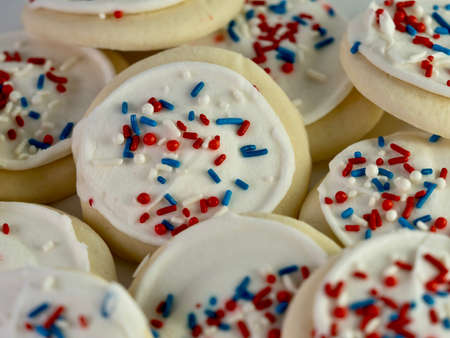 Pile of sugar cookies with white frosting and red, white and blue sprinkles for the 4th of July,...