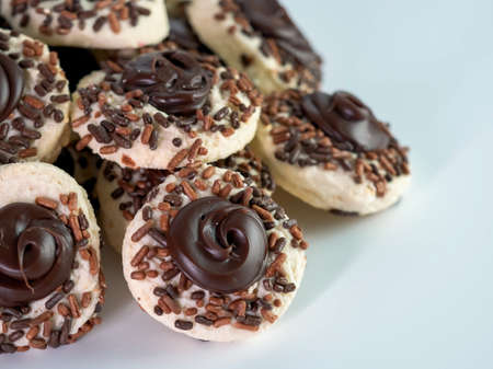 Chocolate thumbprint cookies covered in sprinkles piled up on a white table, delicious sweet treat!