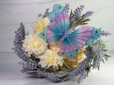 Lavender wreath with white carnations and a mesh blue and purple butterfly decorated with blue gem stones.  Purple flowers and white flowers on a neutral background.  Spring decor.の写真素材