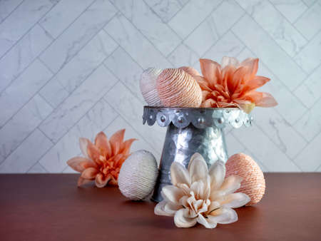 Peach and white string decorated Easter Eggs on a raised metal display with peach dahlia flower...