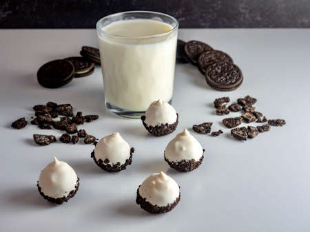 Cookies & Cream Cake Balls, truffle like dessert with a fresh glass of cold milk, a silver spoon, chocolate sandwich cookies and cookie crumbs.の写真素材