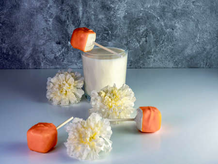 Orange creamsicle cake pops on a stick, orange and white dessert, delicious sweet treat with a glass...