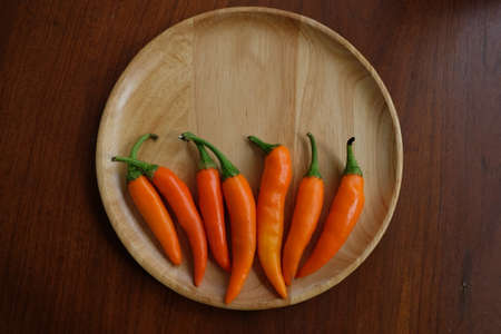 Orange chili in wooden dishの写真素材