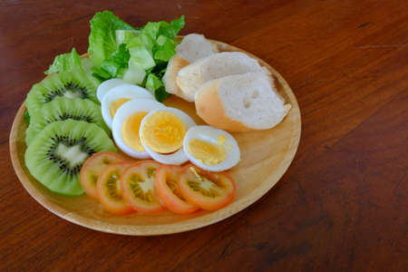 Sliced egg salad serve with vegetable, kiwi, tomato, and crispy bread (on the middle)の写真素材