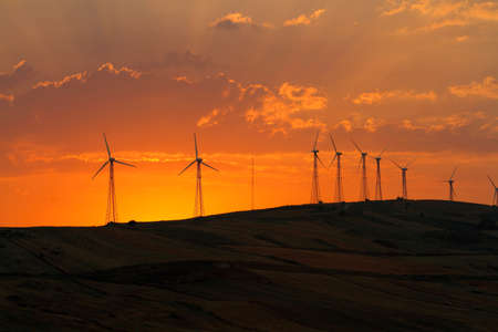 stretched out in the countryside with wind turbines and the setting sunの写真素材