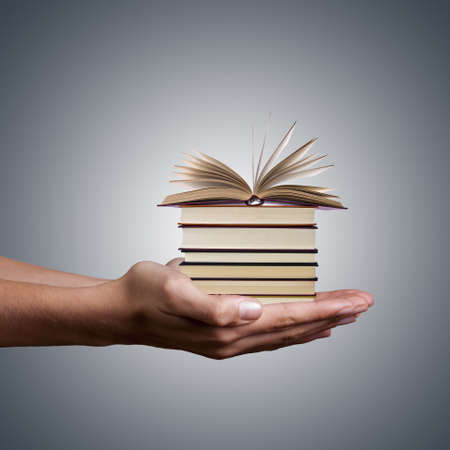 hands holding stacked books on white background