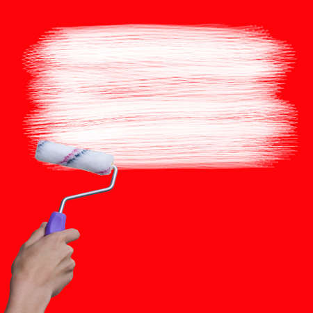 hand with brush painting in white on red wall