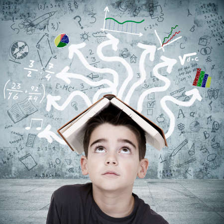 boy with book on his head overwhelmed by the chaos of the subjectsの写真素材