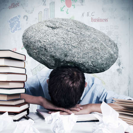 Man at office with stone overhead overworkedの写真素材