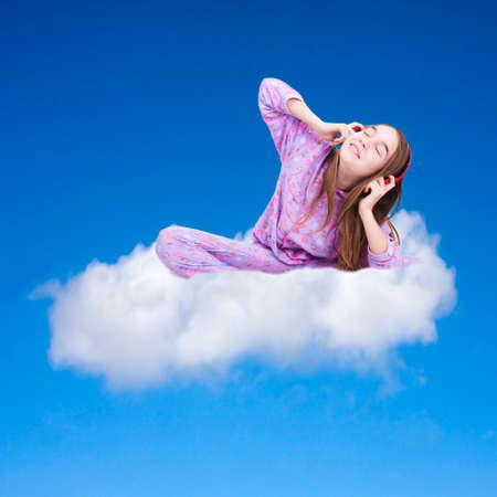 girl sitting listening to music in the cloud in the blue skyの写真素材