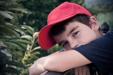 portrait of boy in the foreground with red capの写真素材