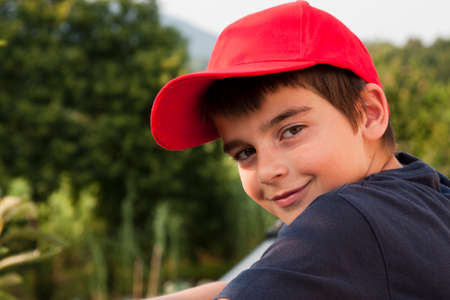 portrait of boy in the foreground with red capの写真素材