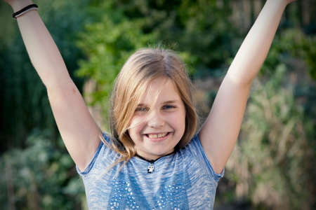 portrait of girl with arms raised in joy.