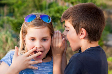 boy and girl counting a secret to the earの写真素材