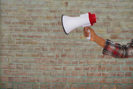 hand with megaphone over brick background